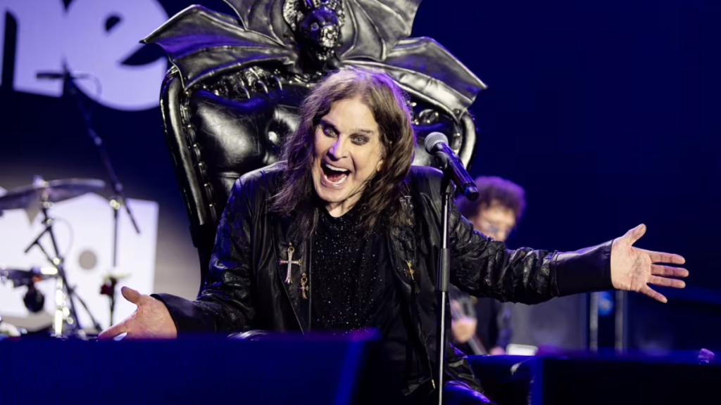 Ozzy Osbourne on stage in his later years, wearing black, with iconic round sunglasses.